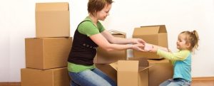 mother helping young daughter pack moving boxes